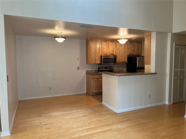 kitchen with appliances with stainless steel finishes, hanging light fixtures, kitchen peninsula, and light hardwood / wood-style flooring