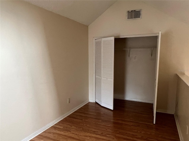 unfurnished bedroom featuring vaulted ceiling, a closet, and dark hardwood / wood-style flooring