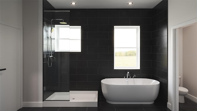 bathroom with a wealth of natural light, tile patterned flooring, separate shower and tub, and toilet