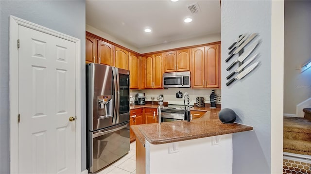 kitchen with light tile patterned floors, appliances with stainless steel finishes, kitchen peninsula, and a breakfast bar