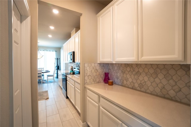 kitchen featuring light tile patterned flooring, stainless steel appliances, decorative backsplash, and white cabinetry