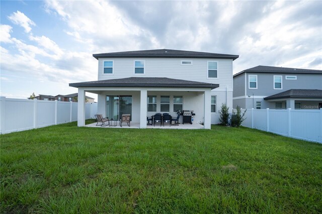 rear view of house with a patio and a yard