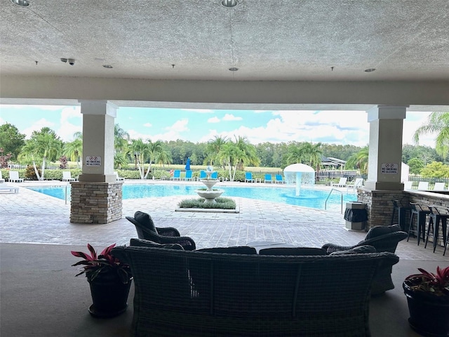 view of pool with a patio, pool water feature, and an outdoor bar