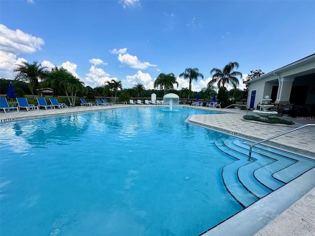 view of swimming pool with pool water feature and a patio area