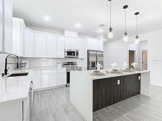 kitchen featuring white cabinetry, stainless steel appliances, sink, and a kitchen island