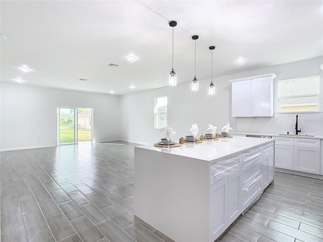 kitchen with sink, a center island, light wood-type flooring, and white cabinets