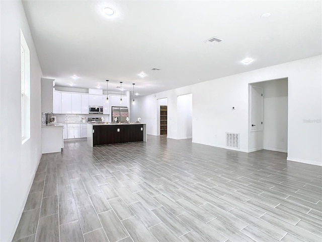 unfurnished living room with sink and light wood-type flooring