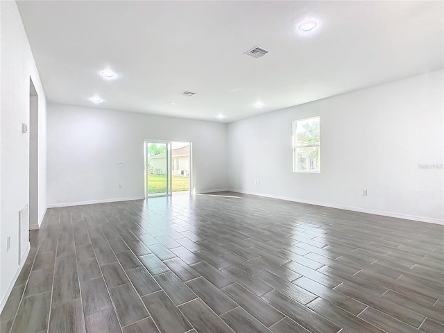 empty room featuring dark wood-type flooring and plenty of natural light