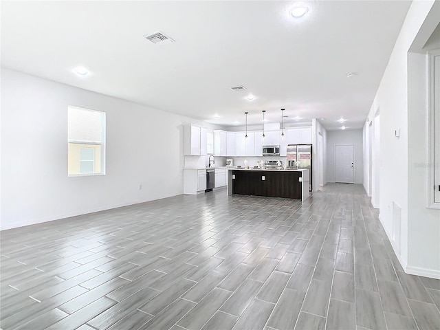 kitchen featuring a kitchen island, light hardwood / wood-style flooring, hanging light fixtures, stainless steel appliances, and white cabinets