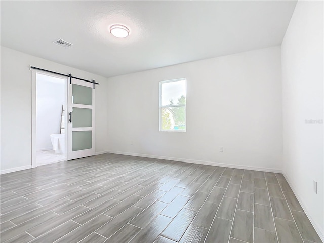 empty room with light hardwood / wood-style flooring and a barn door