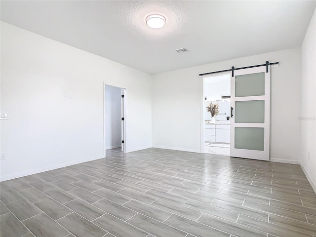 spare room featuring a barn door, a textured ceiling, and light wood-type flooring