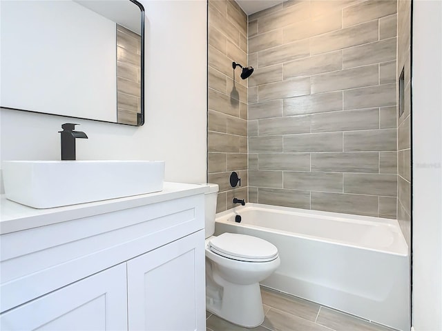 full bathroom with vanity, tiled shower / bath, and toilet