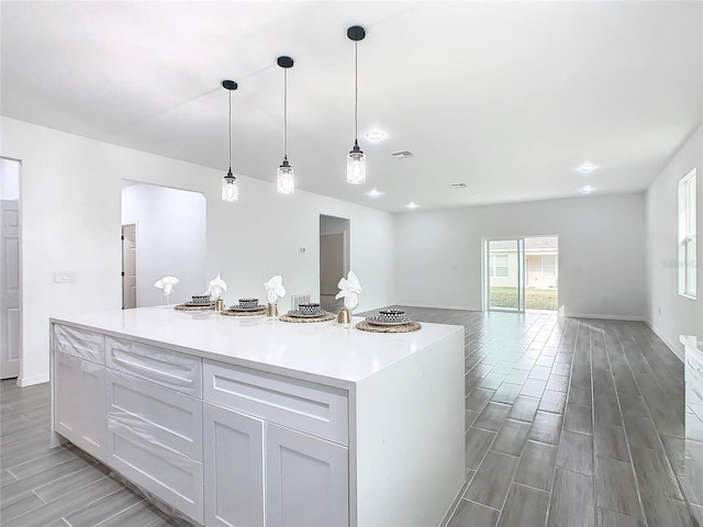 kitchen with hanging light fixtures, a center island, light wood-type flooring, and white cabinets