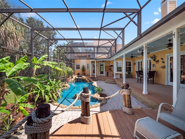 view of swimming pool featuring ceiling fan, glass enclosure, a wooden deck, and a pool with connected hot tub