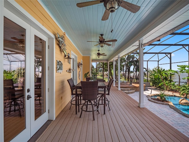 wooden deck featuring glass enclosure, a ceiling fan, a patio, and french doors