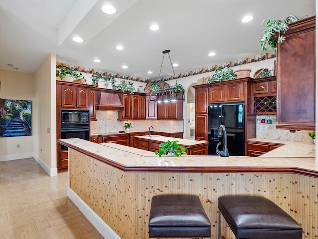 kitchen featuring decorative light fixtures, custom exhaust hood, light countertops, black appliances, and a kitchen breakfast bar