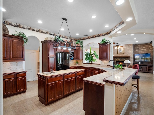 kitchen featuring arched walkways, pendant lighting, light countertops, and freestanding refrigerator