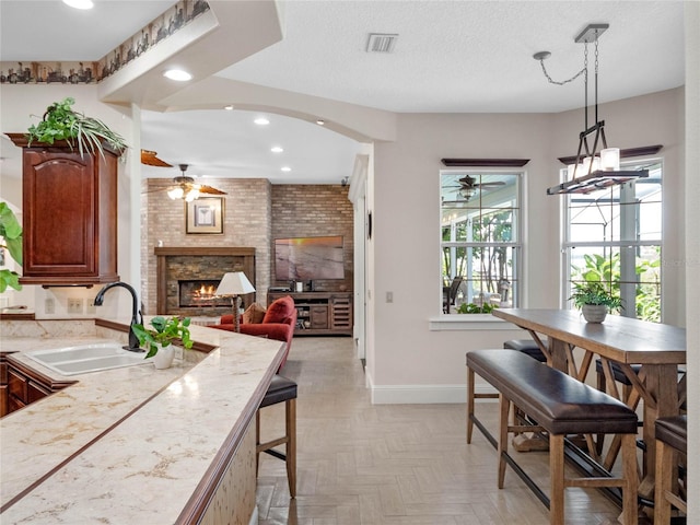 kitchen with a textured ceiling, light countertops, a sink, and pendant lighting