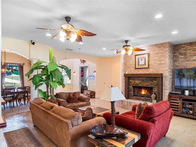 living room with arched walkways, ceiling fan, a fireplace, and recessed lighting