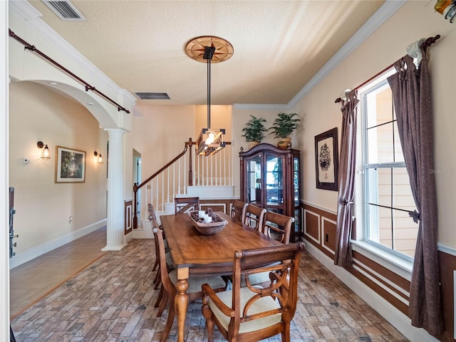 dining room featuring ornate columns, visible vents, arched walkways, and crown molding