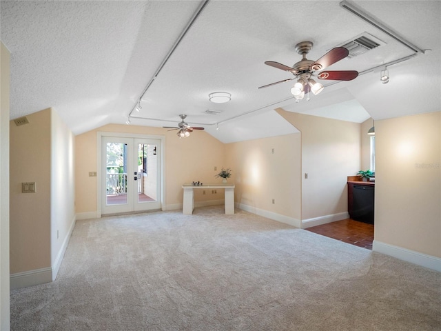 additional living space featuring lofted ceiling, carpet, visible vents, and a textured ceiling