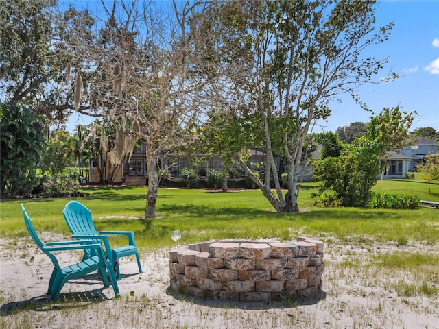 view of property's community featuring an outdoor fire pit and a lawn