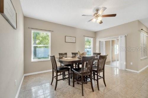 dining space with light tile patterned floors, a ceiling fan, and baseboards