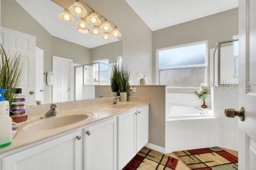 bathroom featuring tile patterned flooring, vanity, vaulted ceiling, and plus walk in shower