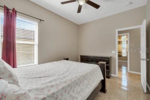 bedroom with baseboards, light tile patterned floors, and a ceiling fan