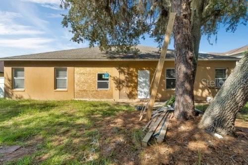back of property with stucco siding and a lawn