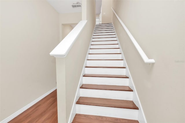 stairs featuring baseboards, visible vents, and wood finished floors