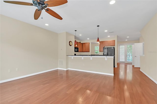 interior space with ceiling fan, decorative light fixtures, light hardwood / wood-style floors, and black appliances