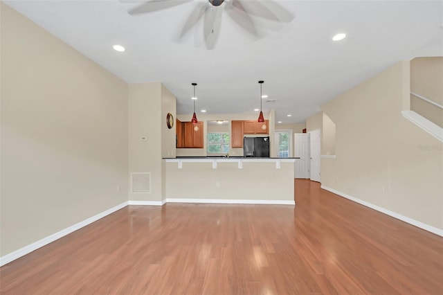 kitchen with open floor plan, light wood-style flooring, a ceiling fan, and freestanding refrigerator