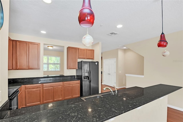 kitchen featuring hanging light fixtures, sink, wood-type flooring, black appliances, and dark stone countertops