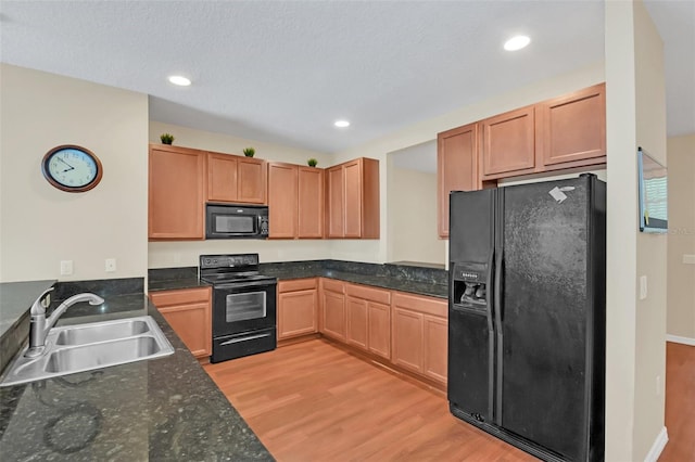 kitchen featuring a textured ceiling, black appliances, light hardwood / wood-style floors, and sink