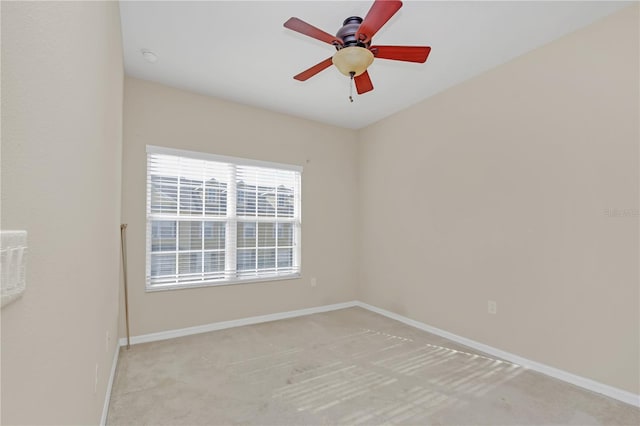 spare room featuring light carpet, baseboards, and ceiling fan