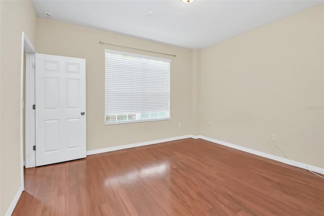 spare room with baseboards, a wealth of natural light, and wood finished floors
