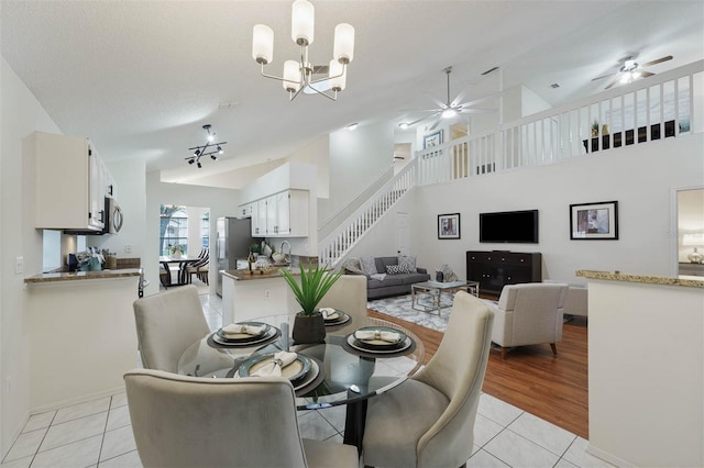 tiled dining space featuring a textured ceiling, sink, vaulted ceiling, and ceiling fan with notable chandelier