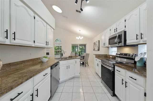 kitchen with lofted ceiling, kitchen peninsula, sink, white cabinetry, and appliances with stainless steel finishes