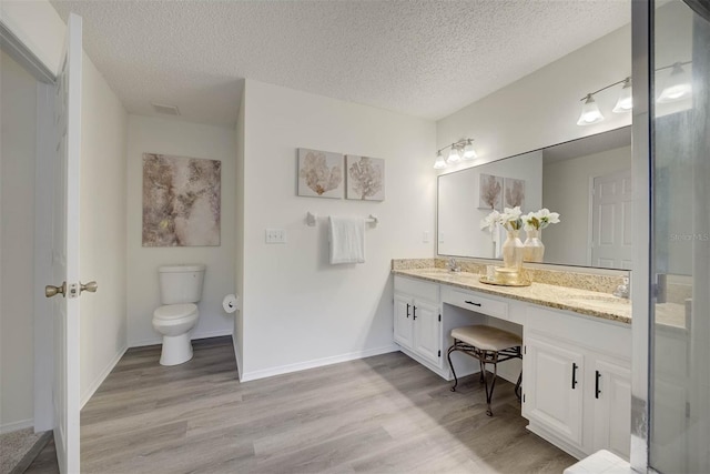 bathroom with toilet, vanity, a textured ceiling, and hardwood / wood-style flooring