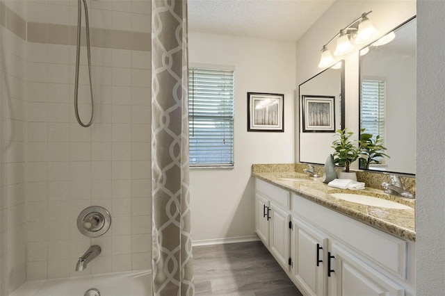 bathroom with vanity, hardwood / wood-style flooring, a textured ceiling, and shower / tub combo