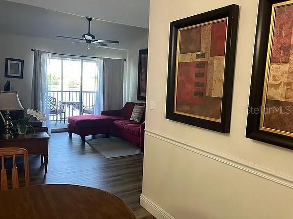 living room featuring dark wood-type flooring and ceiling fan