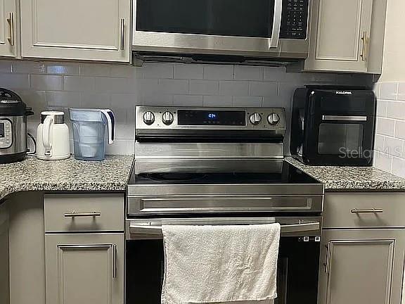 1909 Summer Club Dr Unit 307, Oviedo, FL 32765 - kitchen with stainless steel appliances, tasteful backsplash, light stone countertops, and gray cabinetry