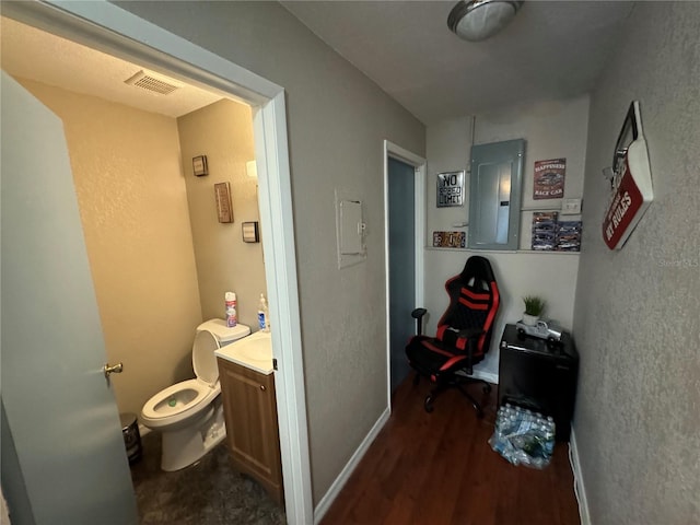 bathroom with electric panel, hardwood / wood-style flooring, vanity, and toilet