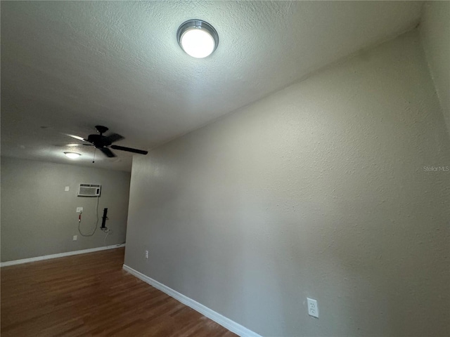 spare room with dark hardwood / wood-style flooring, a textured ceiling, ceiling fan, and a wall mounted air conditioner