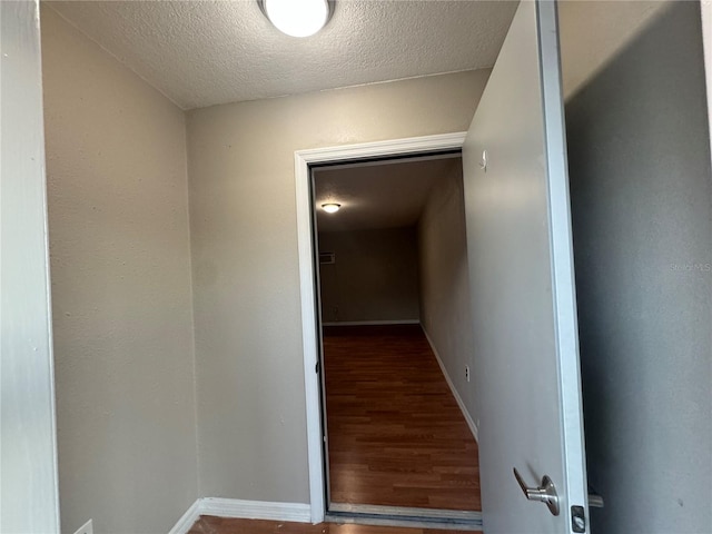 hall with wood-type flooring and a textured ceiling