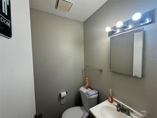 bathroom with a textured ceiling, vanity, and toilet