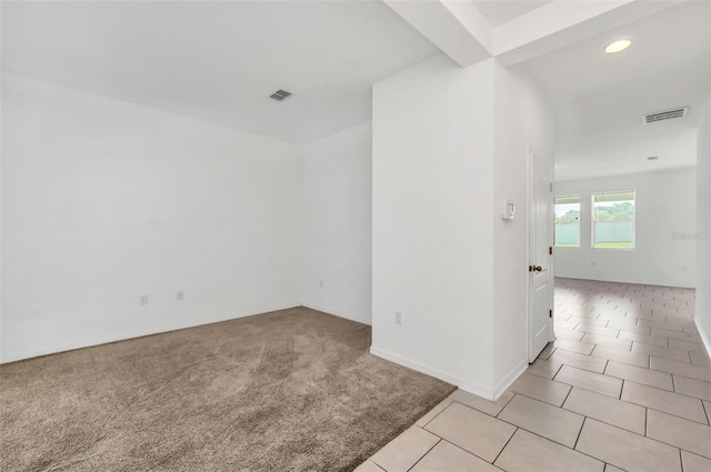 spare room with beamed ceiling and light colored carpet