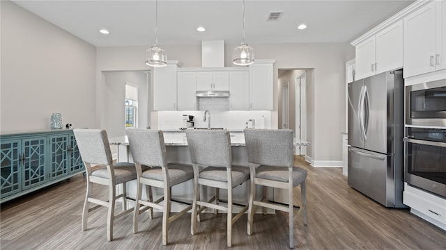 kitchen featuring pendant lighting, white cabinetry, stainless steel appliances, and hardwood / wood-style floors