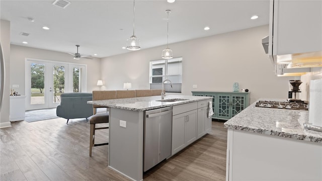 kitchen featuring sink, an island with sink, decorative light fixtures, white cabinets, and appliances with stainless steel finishes